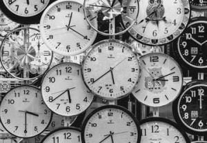 A black and white picture of hundred of clock faces piled on top of each other: a focus on time