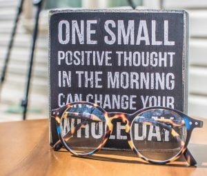 sign with reading glasses in front. Sign says: One small positive thought in the morning can change your whole day.